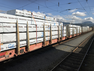 Schienentransport mit Ladung voll verpacktem Holz. Die Verpackung trägt die Aufschrift "binderholz"