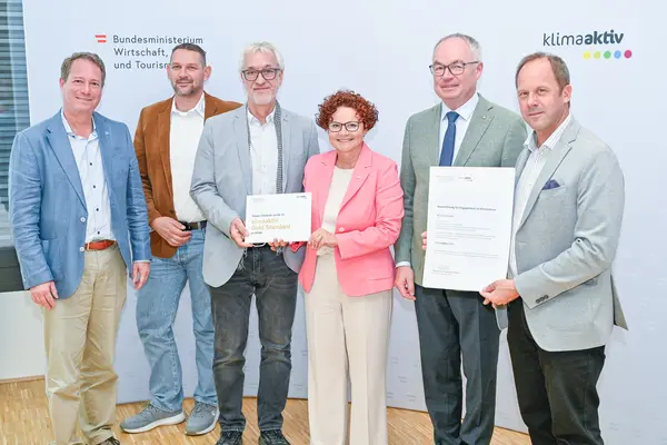 Personen mit Urkunde schauen in die Kamera