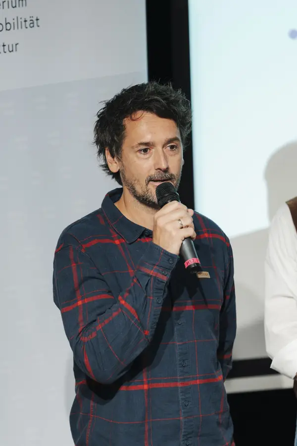 Mann mit Mikro am Podium