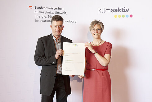 DI Dr. Bettina Bergauer, Stellvertretung Stabsstelle Dialog zu Energiewende und Klimaschutz, zeichnete am 24. März 2022 energieeffiziente Betriebe und Beratungsunternehmen aus.  Ausgezeichneter Betrieb und klimaaktiv Projektpartner: JELD-WEN Türen GmbH  Im Bild: Kurt Buchegger (Leiter Elektrotechnik) mit Bettina Bergauer (BMK)