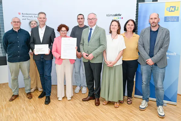 Personen mit Urkunde schauen in die Kamera