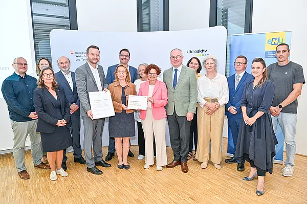 Personen mit Urkunde schauen in die Kamera