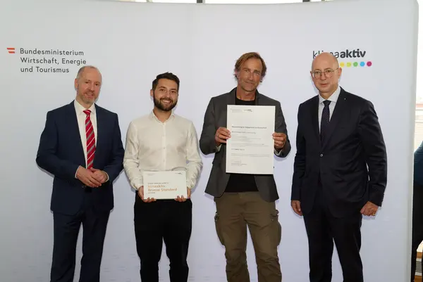 4 Personen mit Urkunde schauen in die Kamera