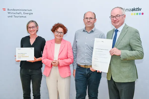 Personen mit Urkunde schauen in die Kamera