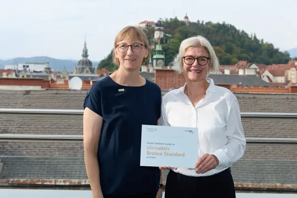 2 Personen mit Urkunde schauen in die Kamera