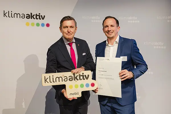 Menschen mit Urkunde und klimaaktiv Schild lächeln in die Kamera