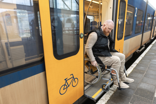 Mann fährt in seinem Rollstuhl vom Zug auf den Bahnsteig