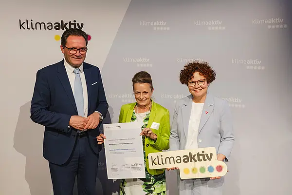 Menschen mit Urkunde und klimaaktiv Schild lächeln in die Kamera