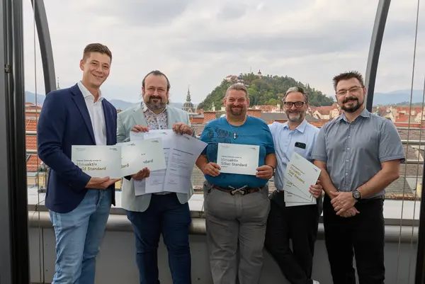 5 Personen mit Urkunde schauen in die Kamera