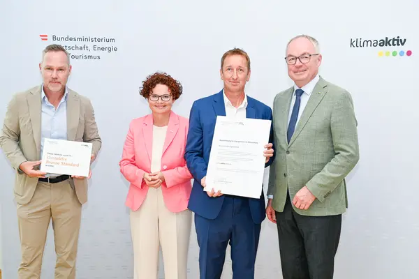 Personen mit Urkunde schauen in die Kamera