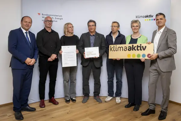 mehrere Personen mit Urkunde in der Hand schauen in die Kamera