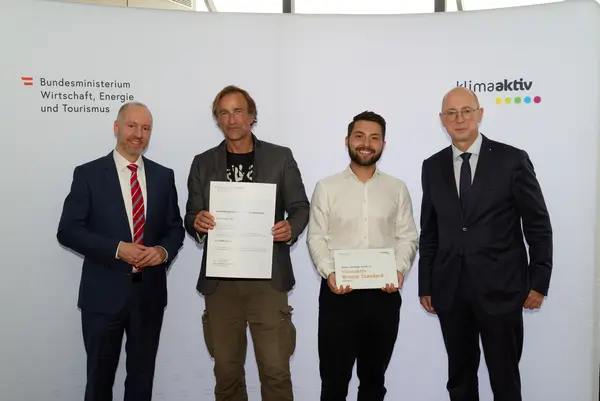 4 Personen mit Urkunde schauen in die Kamera