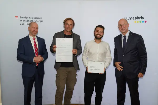 4 Personen mit Urkunde schauen in die Kamera