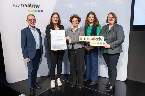 5 Personen mit Urkunde und klimaaktiv Schild schauen in die Kamera