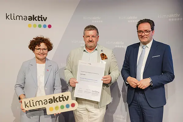 Menschen mit Urkunde und klimaaktiv Schild lächeln in die Kamera