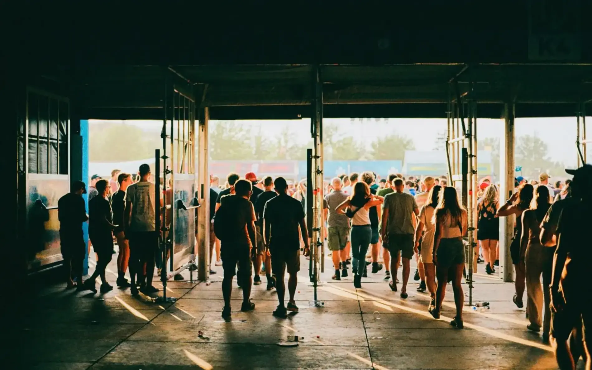 Menschen gehen durch mehrere große Eingänge in Richtung Festivalgelände