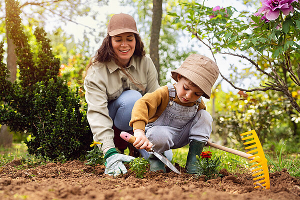 Mutter und Kleinkind graben zusammen den Garten um