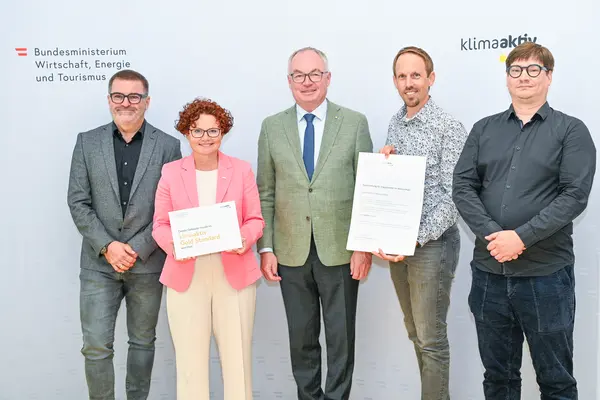 Personen mit Urkunde schauen in die Kamera