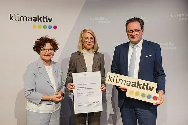 Menschen mit Urkunde und klimaaktiv Schild lächeln in die Kamera