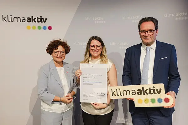 Menschen mit Urkunde und klimaaktiv Schild lächeln in die Kamera