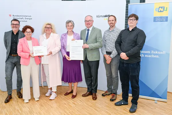 Personen mit Urkunde schauen in die Kamera