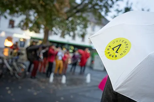 gebrandeter Österreich zu Fuß Regen-Schirm, im Hintergrund verschwommen viele Menschen