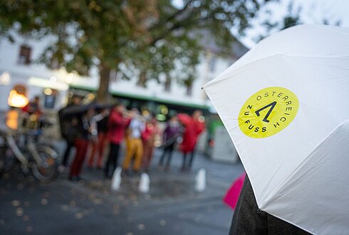 gebrandeter Österreich zu Fuß Regen-Schirm, im Hintergrund verschwommen viele Menschen