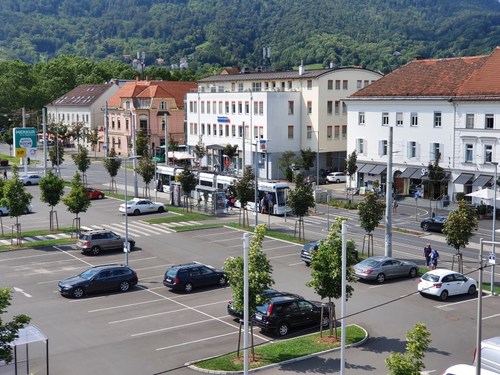 großer Parkplatz, der nur halb mit Autos besetzt ist.