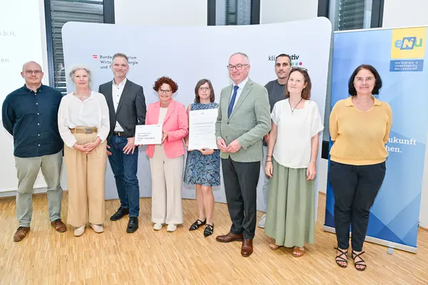 Personen mit Urkunde schauen in die Kamera