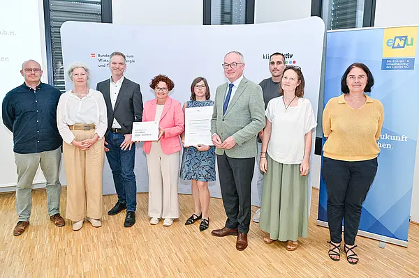 Personen mit Urkunde schauen in die Kamera