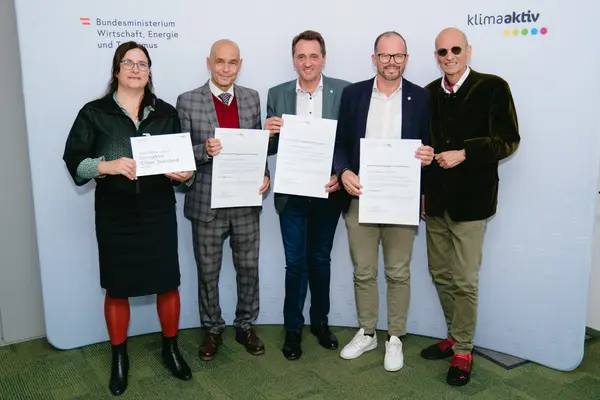 Personen mit Urkunden schauen in die Kamera