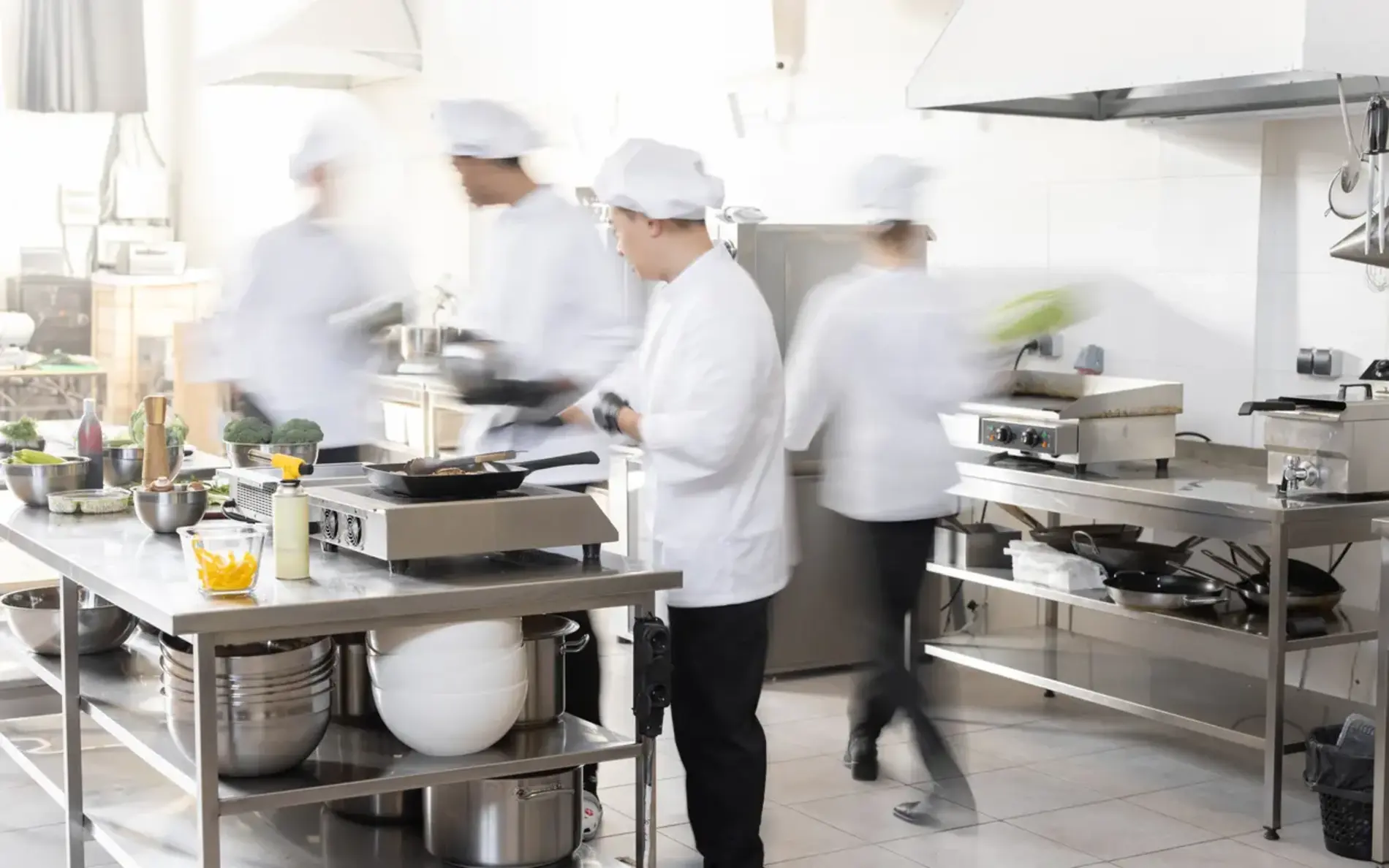 Chefkoch kocht in professioneller Küche. Köche beeilen sich und kochen aktiv Mahlzeiten für das Restaurant. Lange Belichtung mit Bewegungsunschärfe