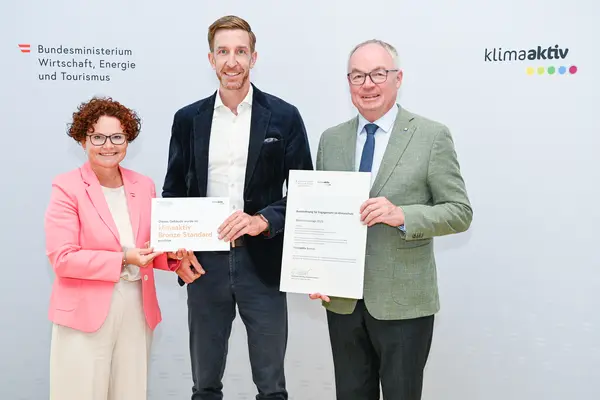 Personen mit Urkunde schauen in die Kamera