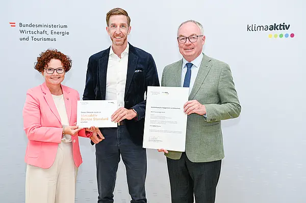 Personen mit Urkunde schauen in die Kamera