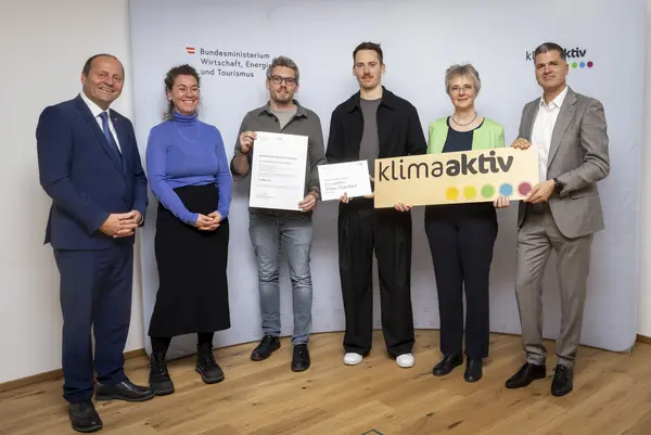 Menschen mit Urkunde schauen in eine Kamera