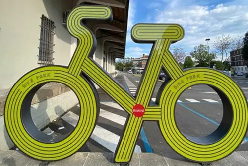 Bild zeigt gelbes Fahrrad-Pictogramm als Leuchtskulptur für die Radstation "Bike Park Rimini" direkt vor dem Bahnhof inklusive Fahrradparken und Fahrradverleih. Mehr Infos unter www.visitrimini.com/de/stylecard-point/bike-park-rimini . 