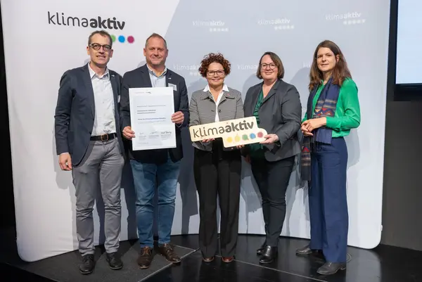 5 Personen mit Urkunde und klimaaktiv Schild schauen in die Kamera