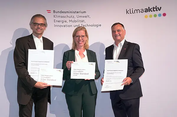 Im Bild: Klimaschutzministerin Leonore Gewessler, Vorstand Helmut Kusternik (meine heimat Gemeinnützige Bau-, Wohn- und Siedlungsgenossenschaft mbH) und Gerhard Kopeinig (ARCH+MORE ZT)