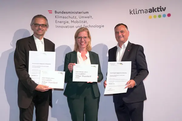 Im Bild: Klimaschutzministerin Leonore Gewessler, Vorstand Helmut Kusternik (meine heimat Gemeinnützige Bau-, Wohn- und Siedlungsgenossenschaft mbH) und Gerhard Kopeinig (ARCH+MORE ZT)
