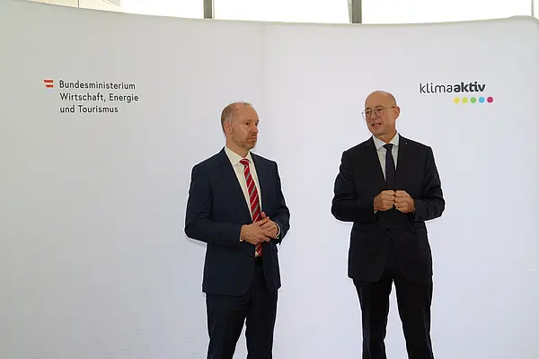 2 Männer in Anzug stehen vor einer Logowand klimaaktiv