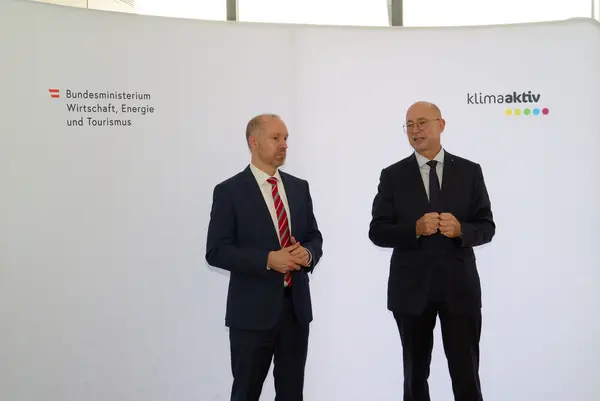 2 Männer in Anzug stehen vor einer Logowand klimaaktiv