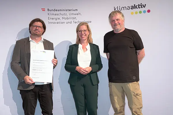 Im Bild: Klimaschutzministerin Leonore Gewessler, Karlheinz Abraham (Drau Wohnbau gemeinn. GmbH), Gerald Werkl (ge.werk Architektur)