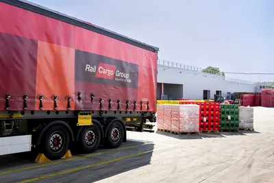 Hinteres Ende von Lastkraftwagen mit Aufschrift Rail Cargo Group, daneben große Getränkegebinde am Boden