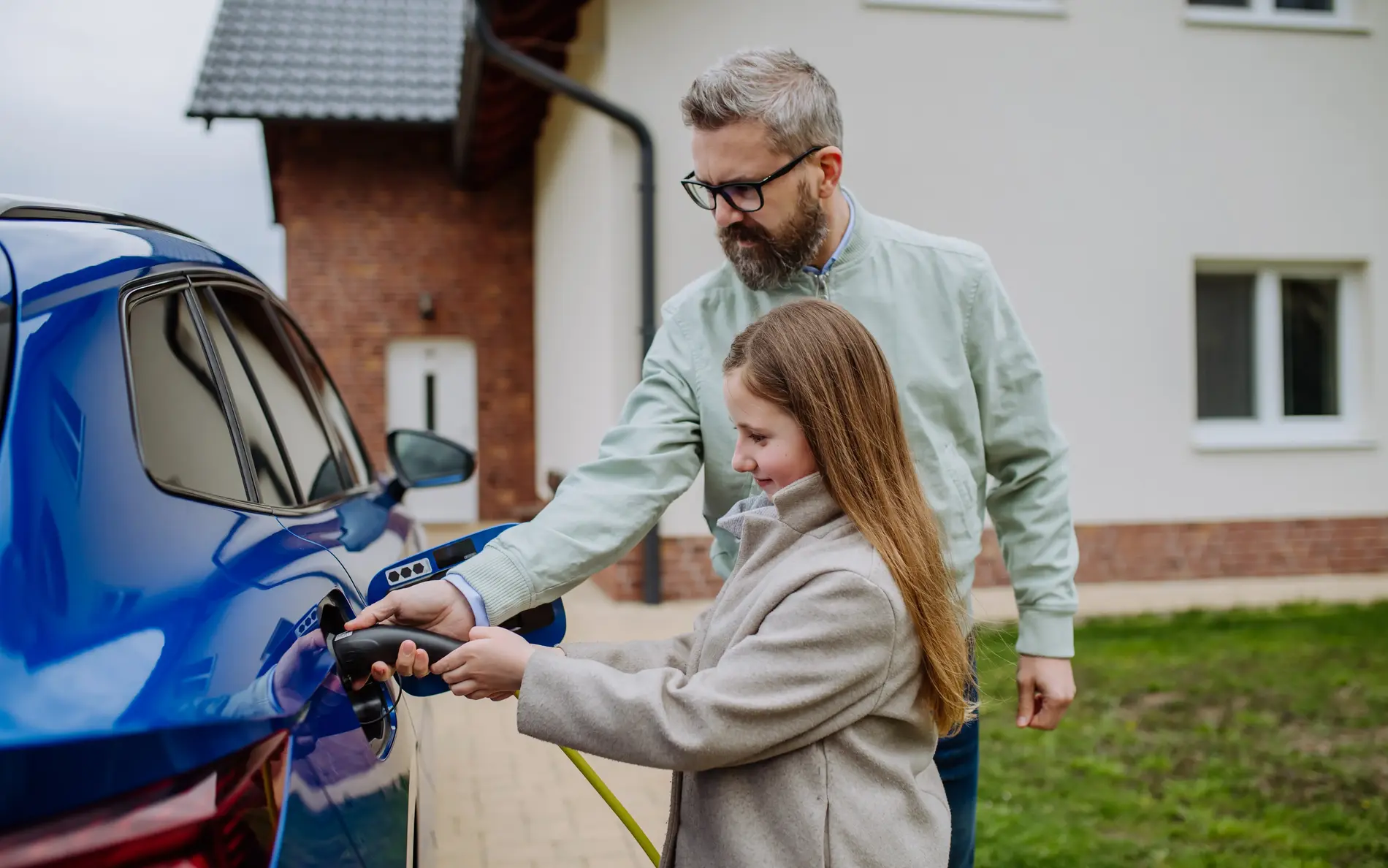 Ein Mann und ein Mädchen betanken gemeinsam ein E-Auto