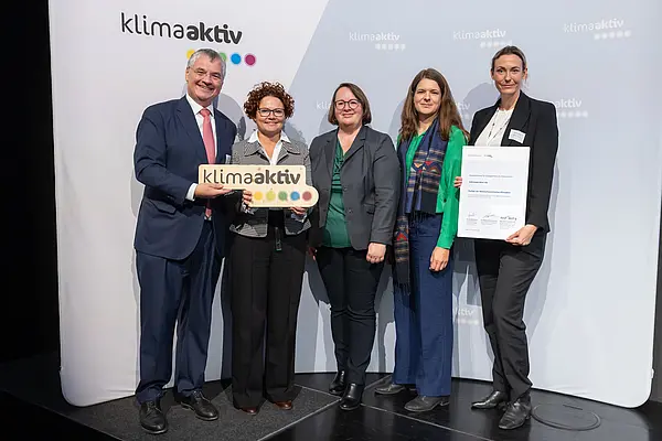 5 Personen mit Urkunde und klimaaktiv Schild schauen in die Kamera