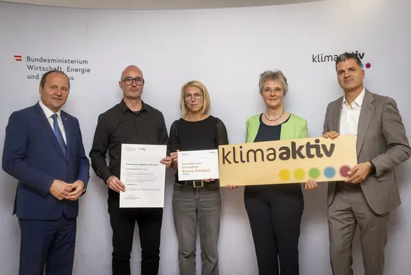 Menschen mit Urkunde schauen in eine Kamera