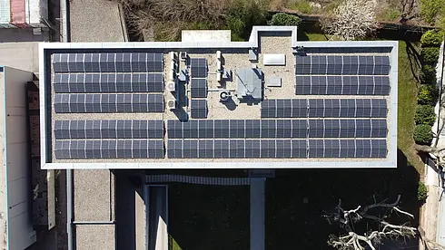 Luftaufnahme eines Daches mit mehreren Reihen von Solarpaneelen und technischen Einrichtungen.
