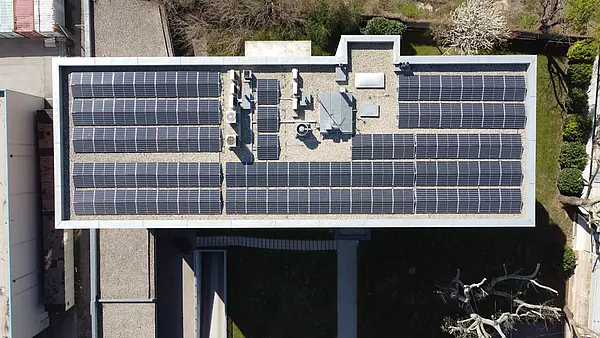 Luftaufnahme eines Daches mit mehreren Reihen von Solarpaneelen und technischen Einrichtungen.