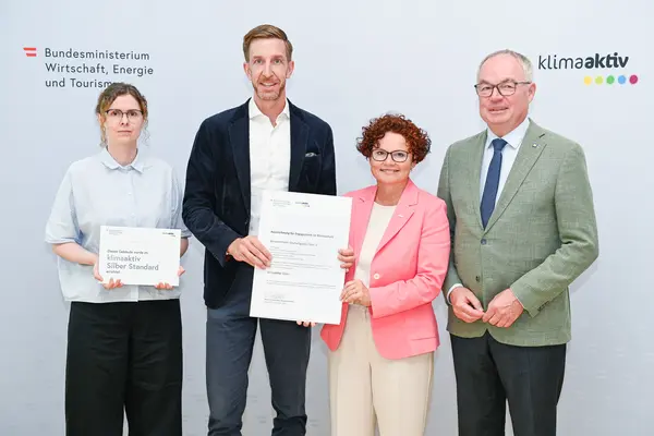 Personen mit Urkunde schauen in die Kamera