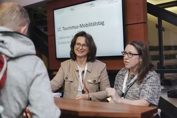 Drei Personen stehen am Stehtisch und sind im Gespräch